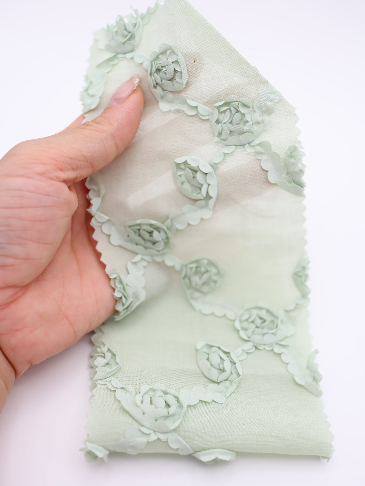 クロスフラワー柄の立体刺繍が施されたグリーン系綿ローン生地。軽やかで柔らかく、ブラウスやワンピースに適した素材