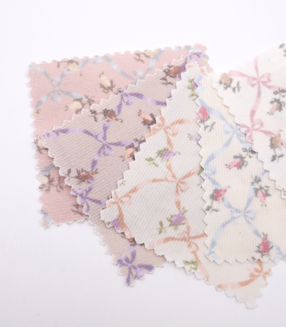 ローズ×リボンプリントコーデュロイ生地布のクローズアップ画像。可愛らしいバラとリボンのプリント柄が特徴的なコーデュロイ素材で、犬服用やバッグ用の手芸に最適な布地