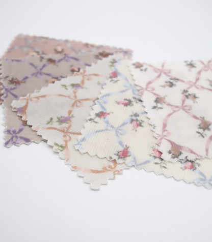 ローズ×リボンプリントコーデュロイ生地布のクローズアップ画像。可愛らしいバラとリボンのプリント柄が特徴的なコーデュロイ素材で、犬服用やバッグ用の手芸に最適な布地