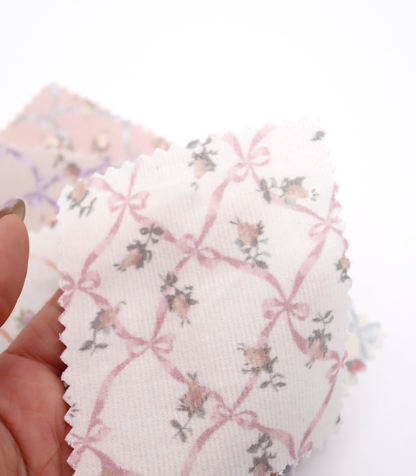 ローズ×リボンプリントコーデュロイ生地布のクローズアップ画像。可愛らしいバラとリボンのプリント柄が特徴的なコーデュロイ素材で、犬服用やバッグ用の手芸に最適な布地